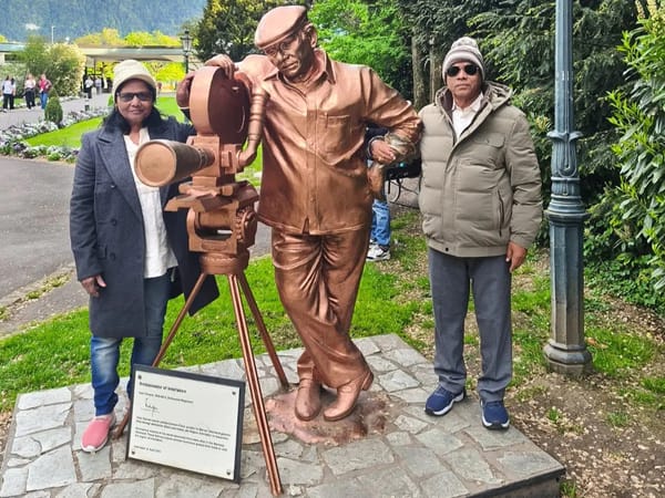 Rajeshwar and Gyanti beside a filmmaker statue in Switzerland
